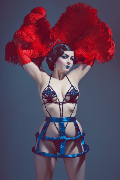 Femme fatale in schicker Lingerie mit roten Federn und betontem Make-up.